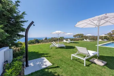 a lawn with chairs and an umbrella and a pool at Aquarama Pool Apt. - Blue in Ixia