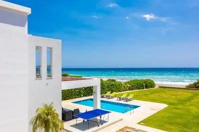 a white house with a swimming pool and the ocean at Villa Dionysos in Lachania