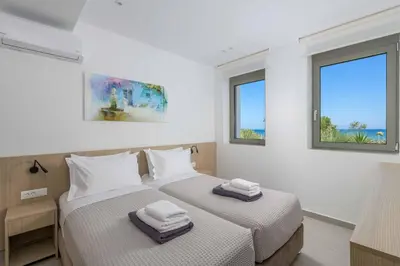 two beds in a room with two windows at Villa Panaxia Akte in Theologos