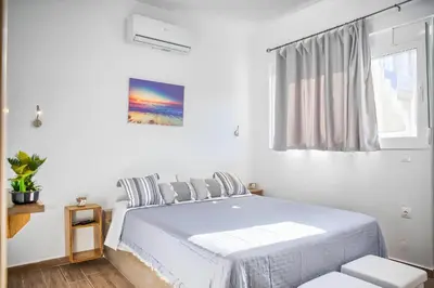 a white bedroom with a bed and a window at La mer stegna in Archangelos