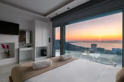 a bedroom with a large bed and a large window at Rhodes SkyLine Suite with out Door Jacuzzi Sea View A1 in Ixia