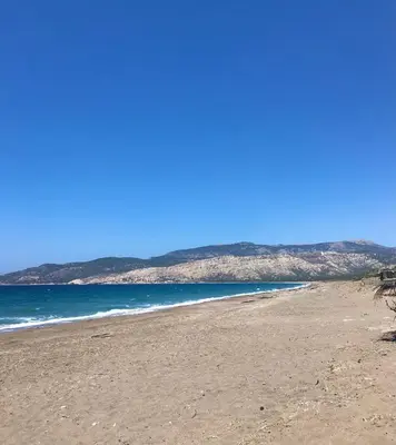 a beach with the ocean and mountains in the background at Lovely independent room in Ecovilla on the beach in Apolakkiá
