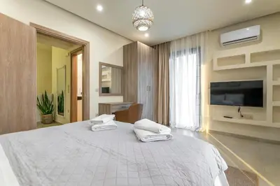 a bedroom with a large white bed and a flat screen tv at Villa Hodaj in Afantou