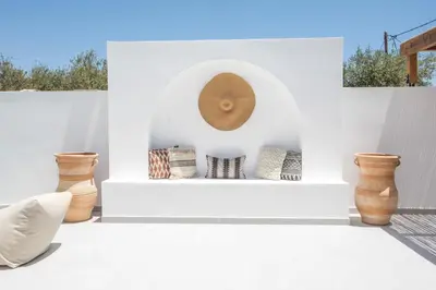 a white patio with vases and a clock on a wall at Zaia Suites & Living , Suite N6 , sea side view in Gennadi