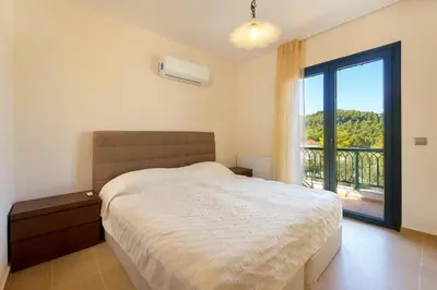 a bedroom with a bed and a large window at Seven Springs Villas in Kolimbia