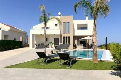a villa with a swimming pool and palm trees at Aetheria Luxury Villa in Kalithies