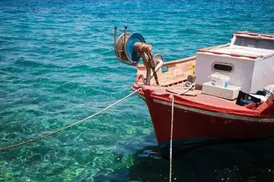 a red boat is tied to the water at Charming Waterfront Studio with swimming access in Halki