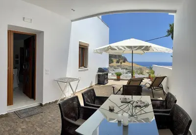 a patio with a table and chairs and an umbrella at Lindos Anatoli Luxury Villa in Líndos