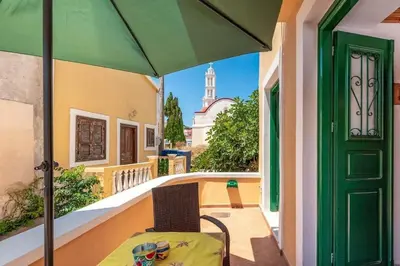 a table and chair on a balcony with an umbrella at Matina's House in Halki