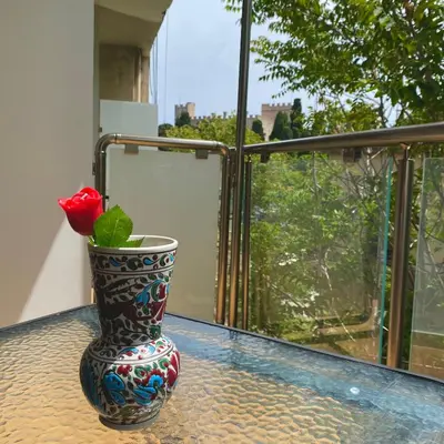 a vase with a rose in it sitting on a table at SEAL of Deer - Castle View - 5 minute walk to the Beach in Rhodes Town