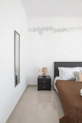 a bedroom with a bed and a nightstand with a mirror at Katerina family Apartment in Archangelos