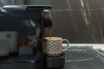 a coffee maker pouring coffee into a coffee cup at Residence City Luna in Rhodes Town