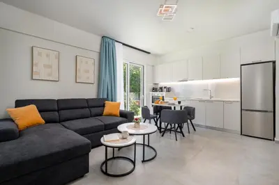 a living room with a couch and a kitchen at Duo Verde Celine Garden Apartment in Kremasti