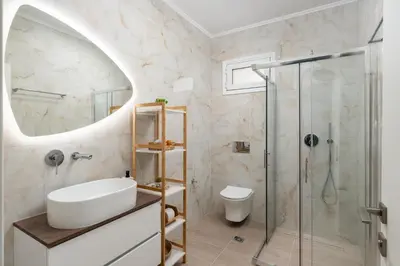 a bathroom with a sink and a shower at Duo Verde Celine Garden Apartment in Kremasti