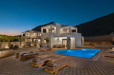 a villa with a swimming pool at night at Amani Villas Lindos in Líndos