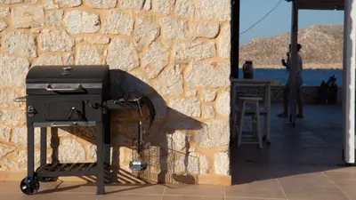 a charcoal grill sitting next to a stone wall at Villa Aristoteles in Halki