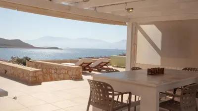 a patio with a table and chairs and a view of the water at Villa Blu Majestic beach villa in Halki