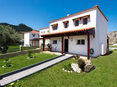 a white house with a green lawn in front of it at Holiday Home Haus in Kolympia mit Parkplatz und Bergblick by Interhome in Kolimbia
