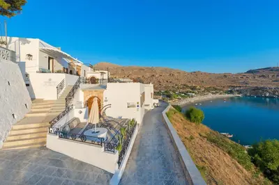 a white house with a view of a lake at Lindos Shore Superior Studio in Líndos