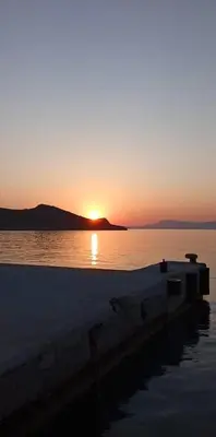 a sunset over a body of water with a boat at Occasus Room in Halki