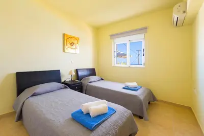 a room with two beds and a window at Athoniki Villas in Kalathos