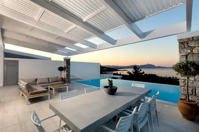 a patio with a table and chairs and a couch at Villa Serene with swimming pool in Lindos in Líndos