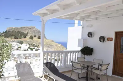 a patio with a table and chairs on a balcony at Bakia Lindos in Líndos