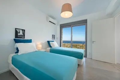 two beds in a bedroom with a view of the ocean at Luxury Villa Hera with Private Pool in Afantou