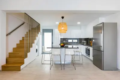 a kitchen with a dining room table and a staircase at Villa Phos with swimming pool in Lindos in Líndos