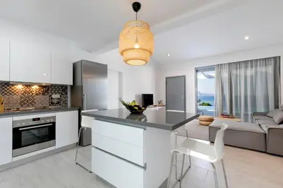 a kitchen and living room with white cabinets and a couch at Villa Estella with pool & jacuzzi in Lindos in Líndos