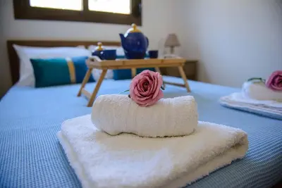 a towel with a rose on top of a bed at Blue Bay Villas , Ground Floor in Archangelos