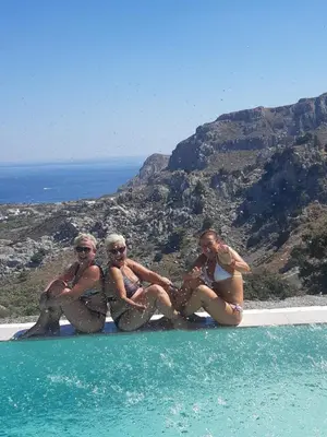 a group of women sitting on the edge of a swimming pool at Bouganville apartment Stegna in Archangelos