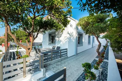 a white house with trees and a sidewalk at Dias Luxury Homes in Koskinou