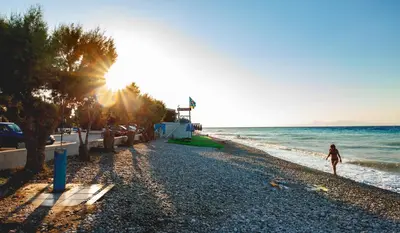 a woman walking on the beach at sunset at CHAMBRE BLEUE in Ialyssos