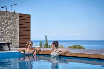 two women sitting in a swimming pool at Luxury Rhodes Villa Amel Villa Sea View Private Swimming Pool in Rhodes Town