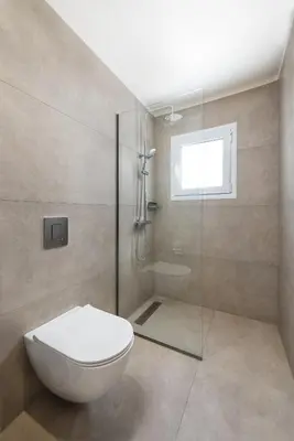 a bathroom with a toilet and a glass shower at ANASTASIOS HOUSE STEGNA - UP FLOOR in Archangelos