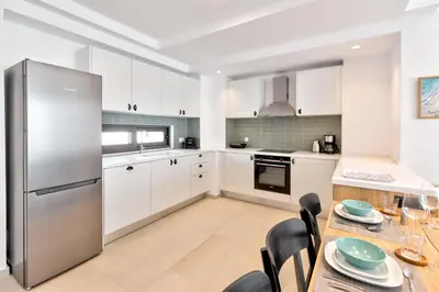 a kitchen with white cabinets and a stainless steel refrigerator at Villa Lara AmberBlue Pefkos in Pefki Rhodes