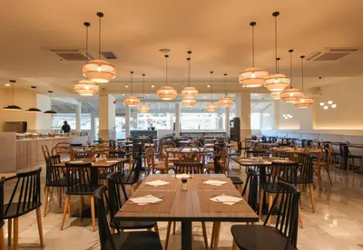 a restaurant with wooden tables and chairs and chandeliers at Villa Mare by Delfinia Resort in Kolimbia