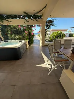 a patio with a hot tub and a table and chairs at Amaryllis front beach hotel in Lardos