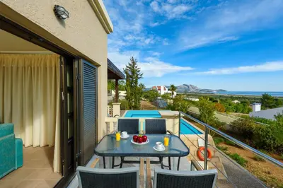 a patio with a table and chairs on a balcony at Aegean Blue Villa's - All Inclusive & Water park in Kalathos