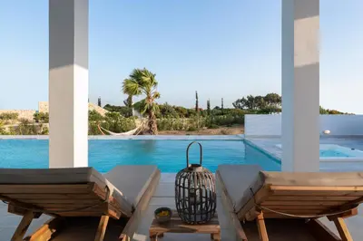 a patio with two chairs and a swimming pool at Seastar Villa Large Pool & Jacuzzi Retreat in Lachania
