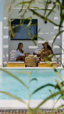 three women sitting on a bench next to a pool at Seastar Villa Large Pool & Jacuzzi Retreat in Lachania