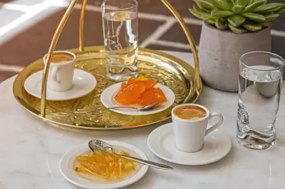 a table with two cups of coffee and a tray of food at Amada Colossos Resort in Faliraki