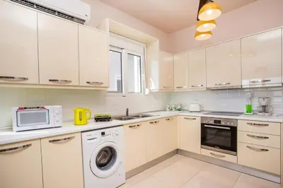 a kitchen with white cabinets and a washer and dryer at Villa Regina - Double Pool Paradise in Lachania