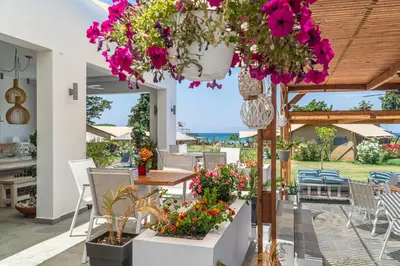 a patio with flowers and a table and chairs at LOGOS Beach Village in Theologos